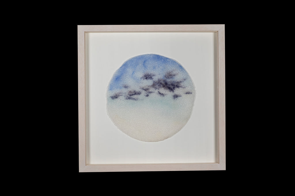 Framed glass artwork by Longwill Studio photographed on a black background. The artwork is a disc of fused glass inspired by morning skies